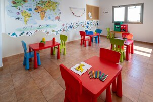 Un aula con sillas y mesas coloridas, un mapa mundial en la pared y material educativo en los escritorios.