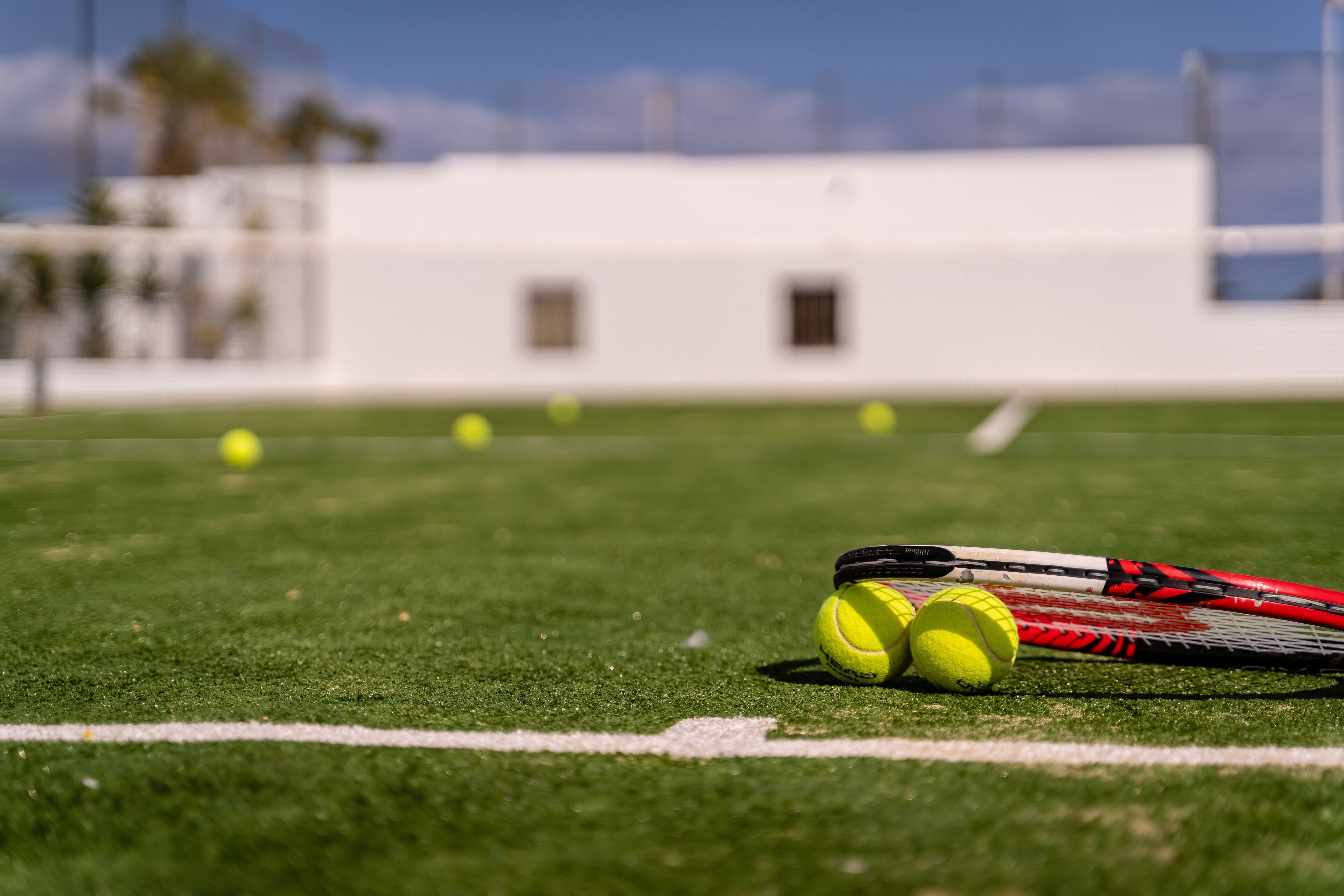 A sports field with a tennis racket and tennis balls.