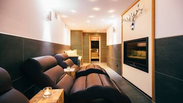 A modern spa room with leather seating, a small table with a candle, and a fireplace.