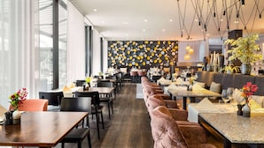 Un restaurante moderno con un amplio comedor, asientos acolchados y una pared con diseño.