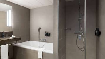 Un baño moderno con bañera, ducha y zona de ducha con cerramiento de vidrio.