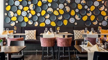 L’intérieur d’un restaurant, avec un mur décoré d’assiettes, des sièges rembourrés et des tabourets de bar.