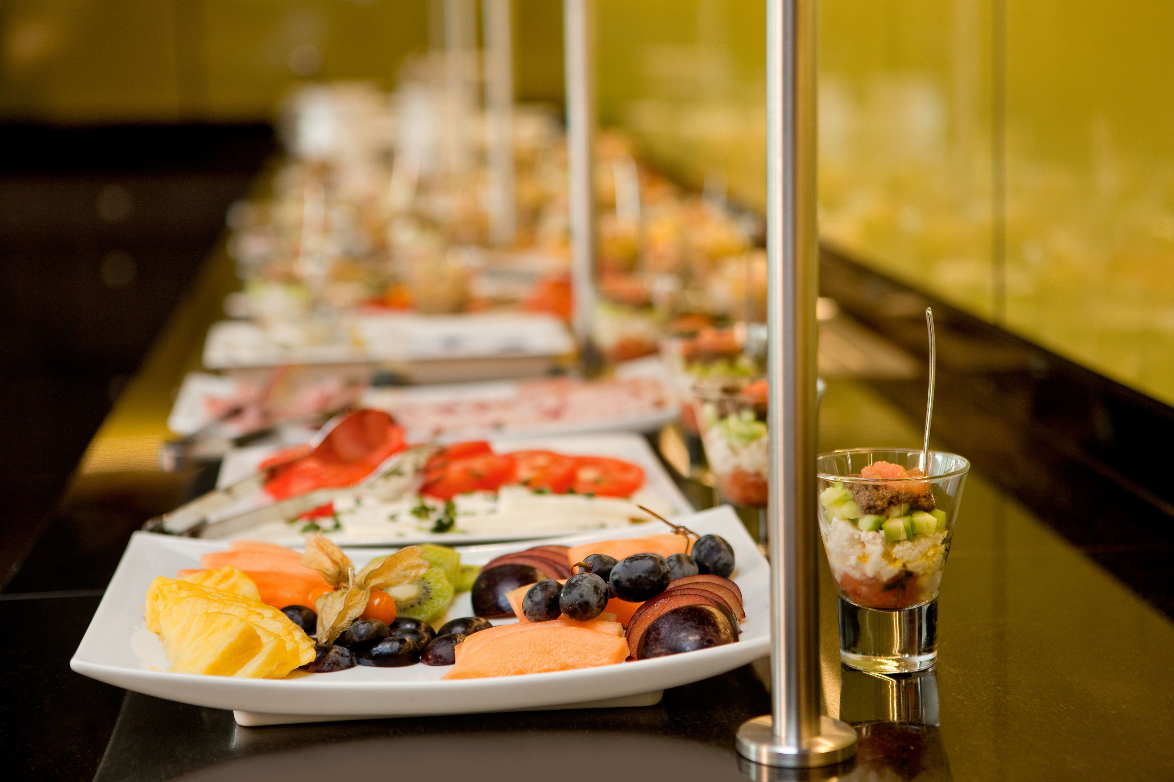 Un buffet con diverse pietanze, tra cui frutta, verdura e bevande.
