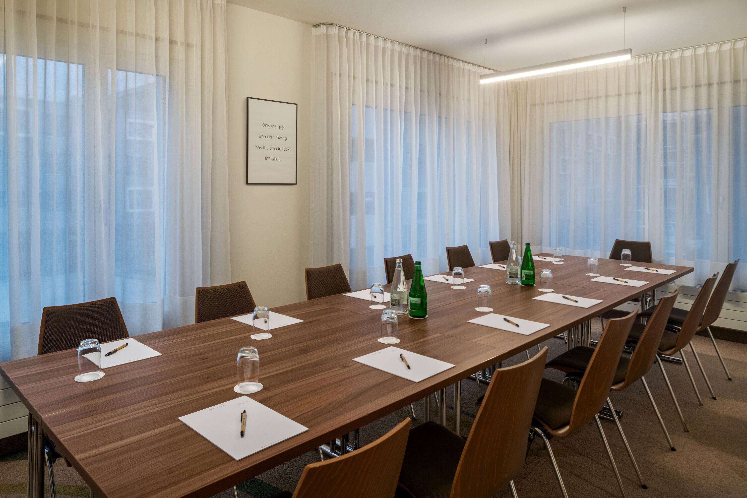 A conference room with a long table, chairs, and a framed quote on the wall.