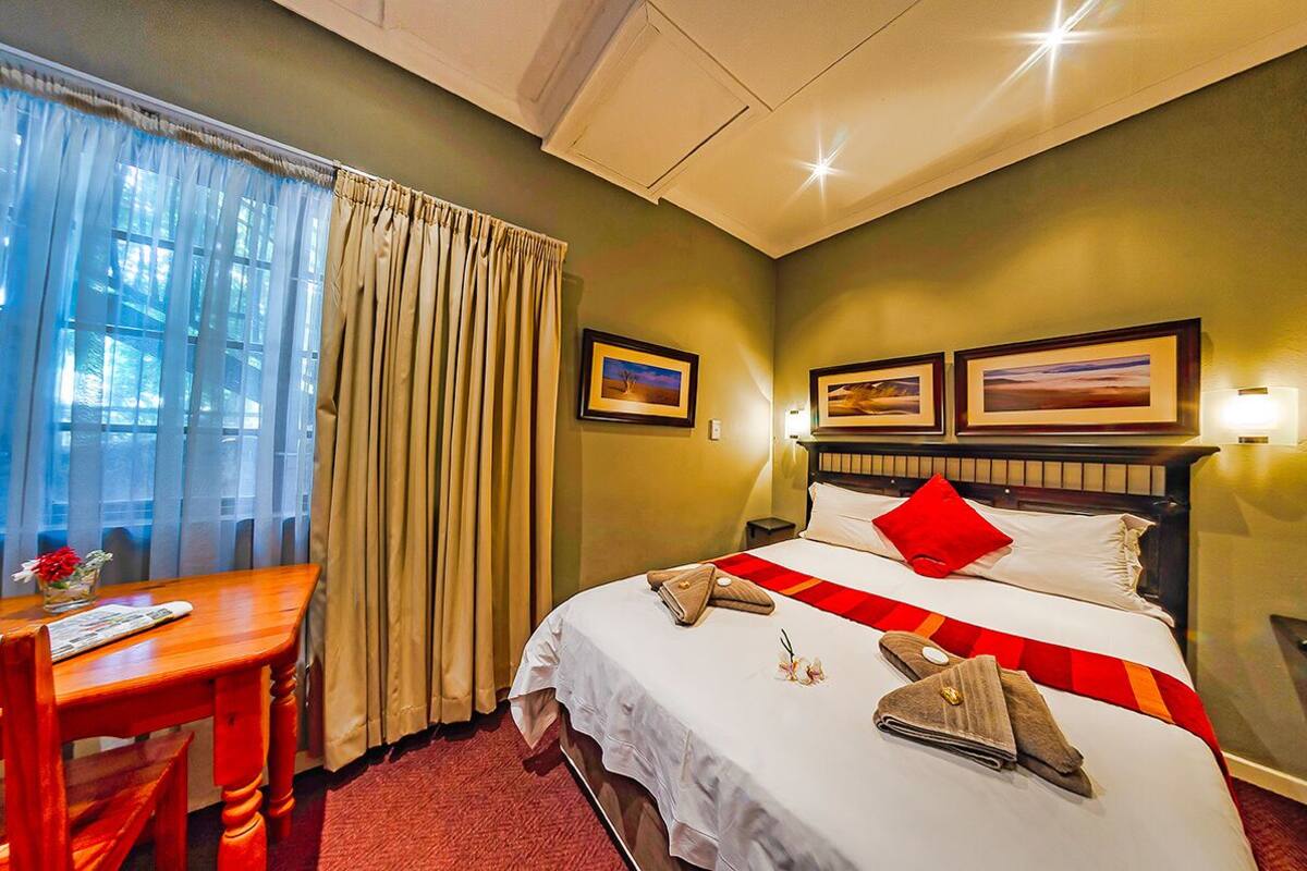 Ein Hotelzimmer mit Bett, Schreibtisch und einem Vorhangfenster.