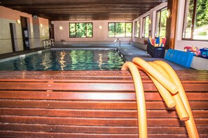 An indoor swimming pool with wooden flooring and a clear view of the surrounding area.