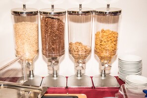 A food dispensing station with four dispensers, each containing different types of grains and cereals.