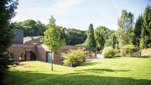 Een modern bakstenen gebouw met een schuin dak, omringd door een verzorgd gazon en bomen.