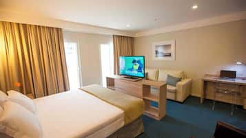 A hotel room with a bed, a desk with a computer, a television, and a sofa.
