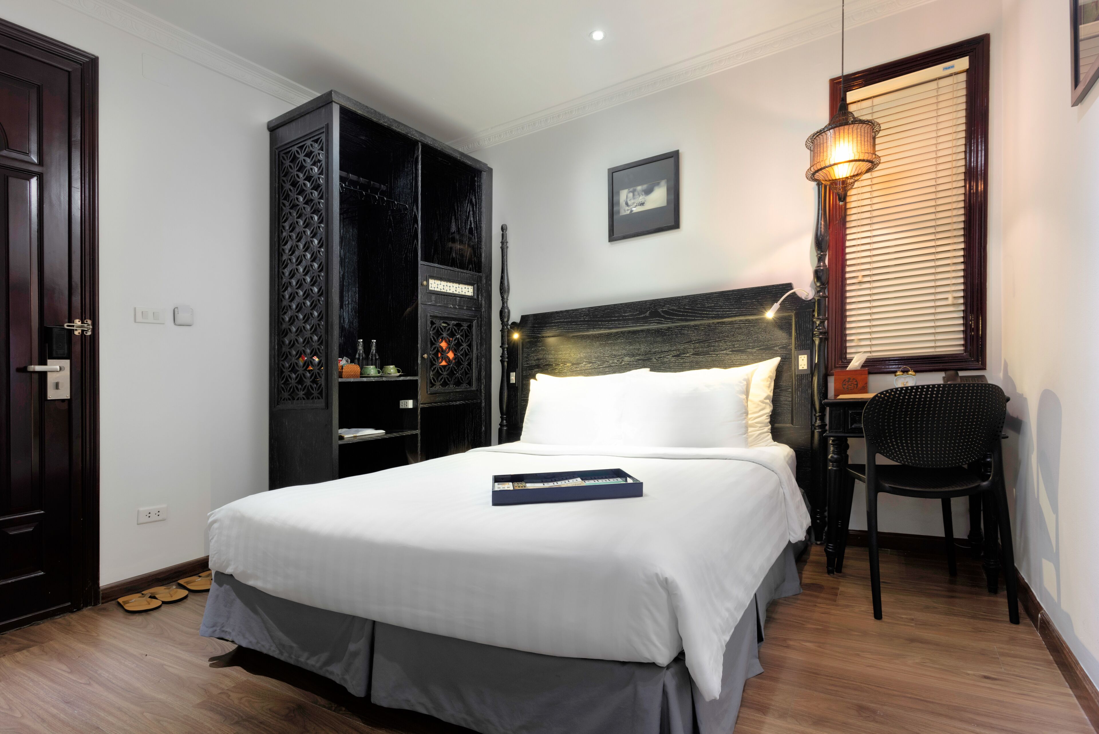 A hotel room with a bed, a desk, and a wardrobe.