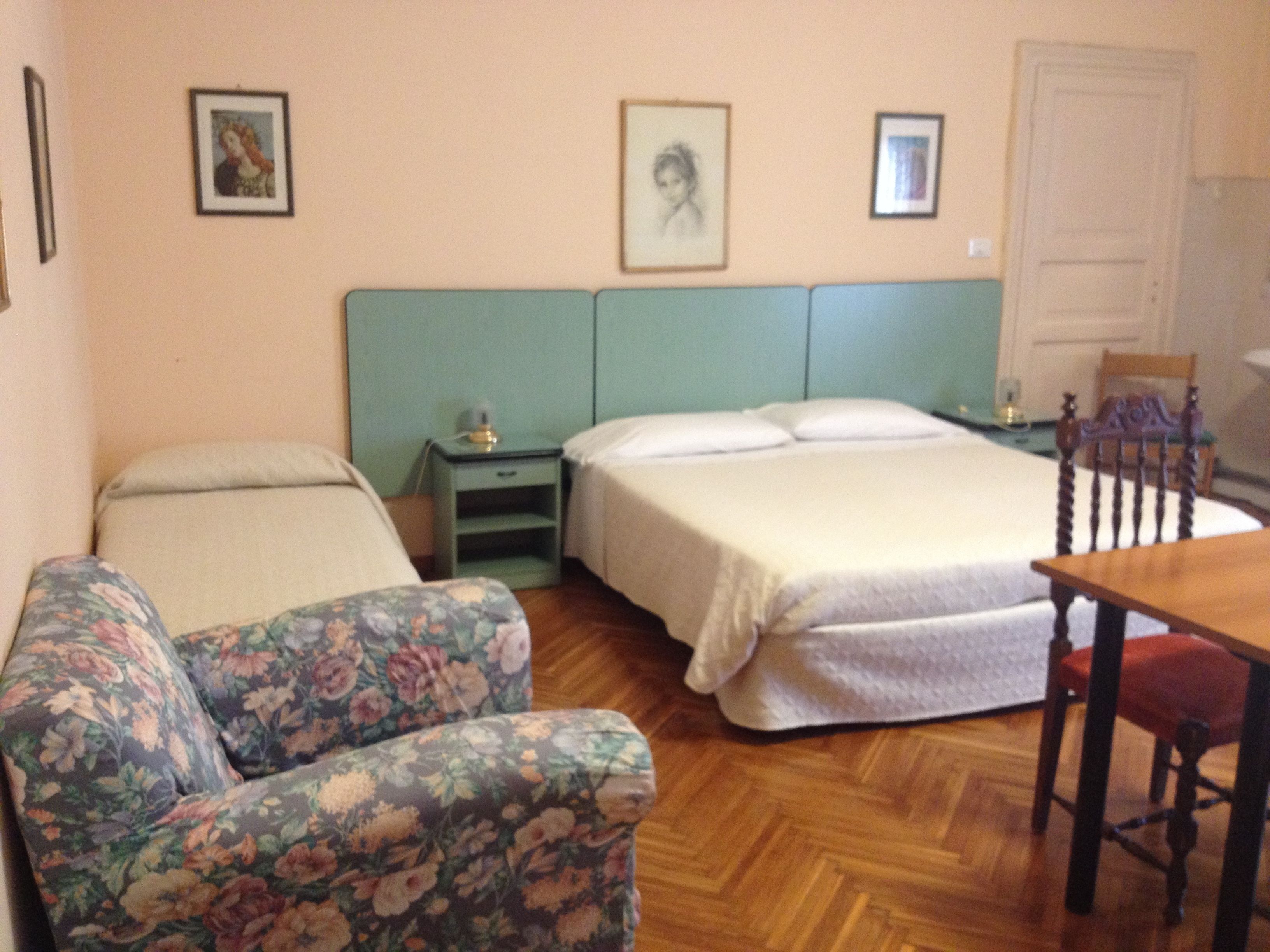 Una habitación con dos camas, una silla, una mesa y una mesita de noche.