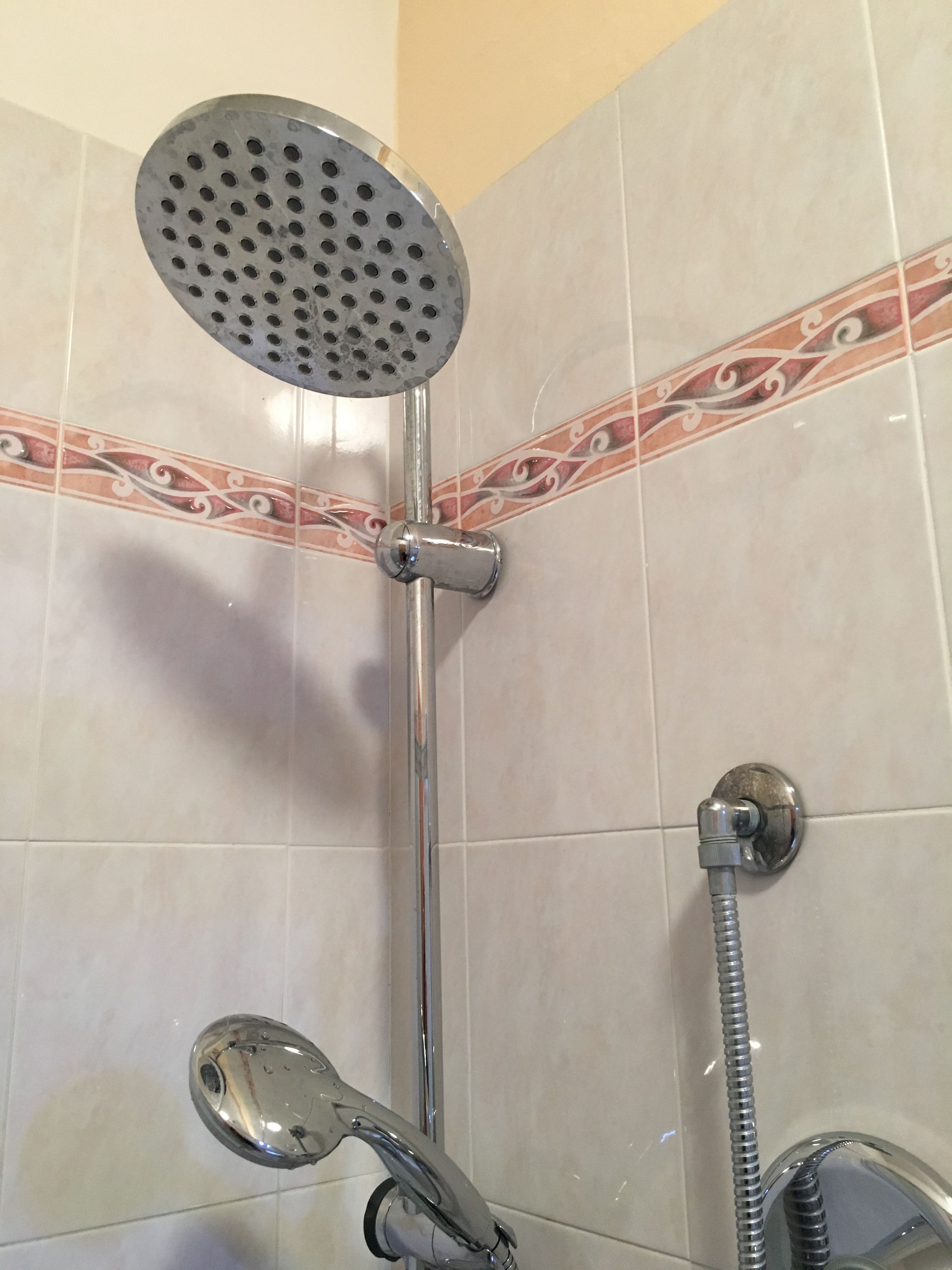 A shower with a handheld showerhead and a handheld hose.