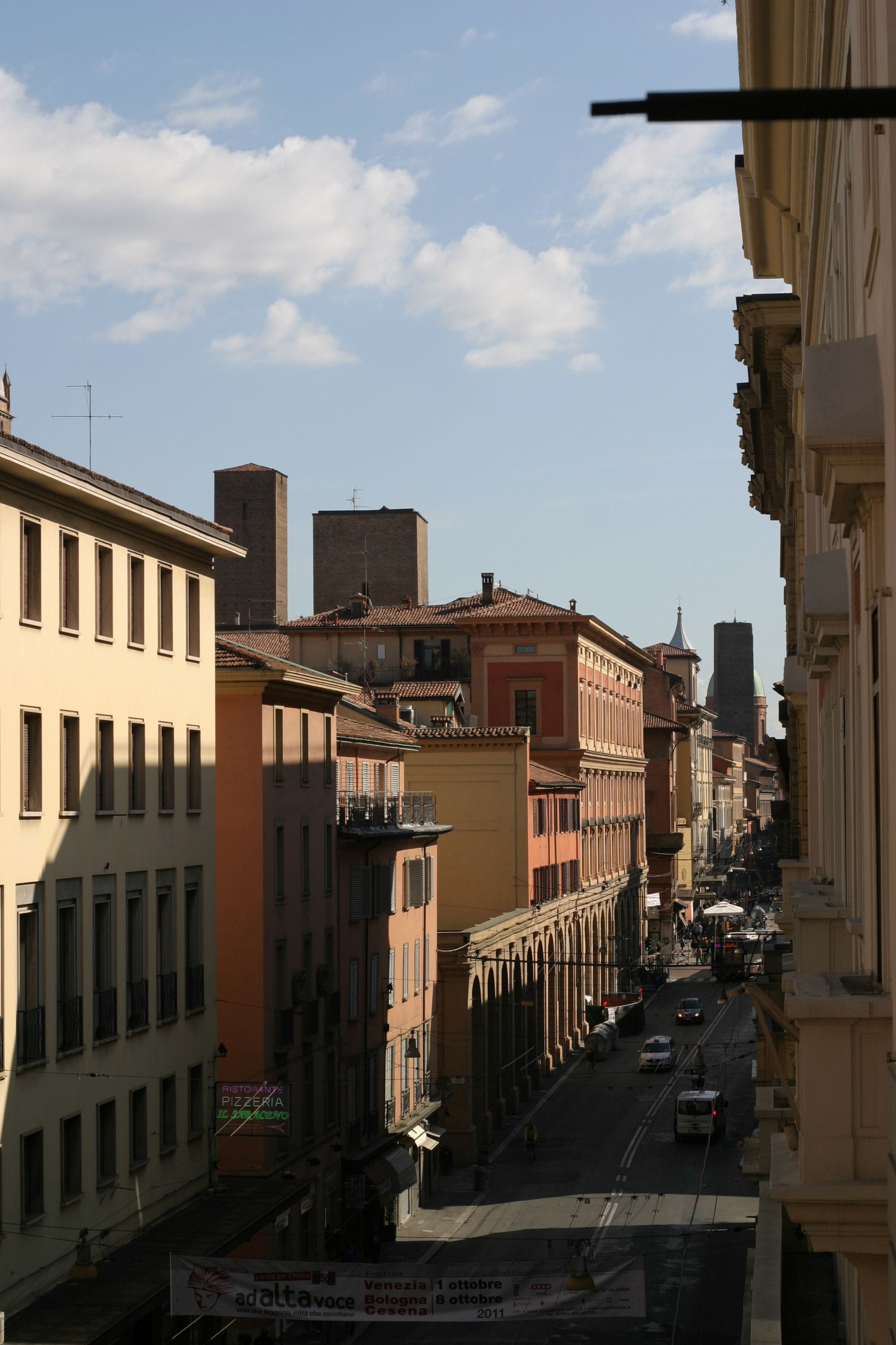 A street view with buildings, a clear sky, and a sign for a pizzeria.