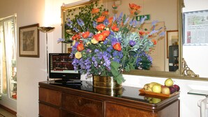A wooden desk with a television, a vase of flowers, and a fruit bowl. - Albergo Panorama (Bologna)