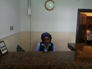A reception area with a clock on the wall, a counter, and a framed notice on the wall.