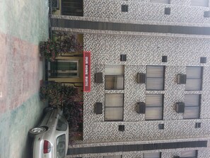 A multi-story building with a patterned facade, a car parked in front, and a sign reading "Our Home Suite".