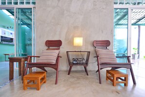 A room with two wooden chairs with striped cushions, a small wooden table, and a radio on a stand. - Just Fine Krabi (Krabi)