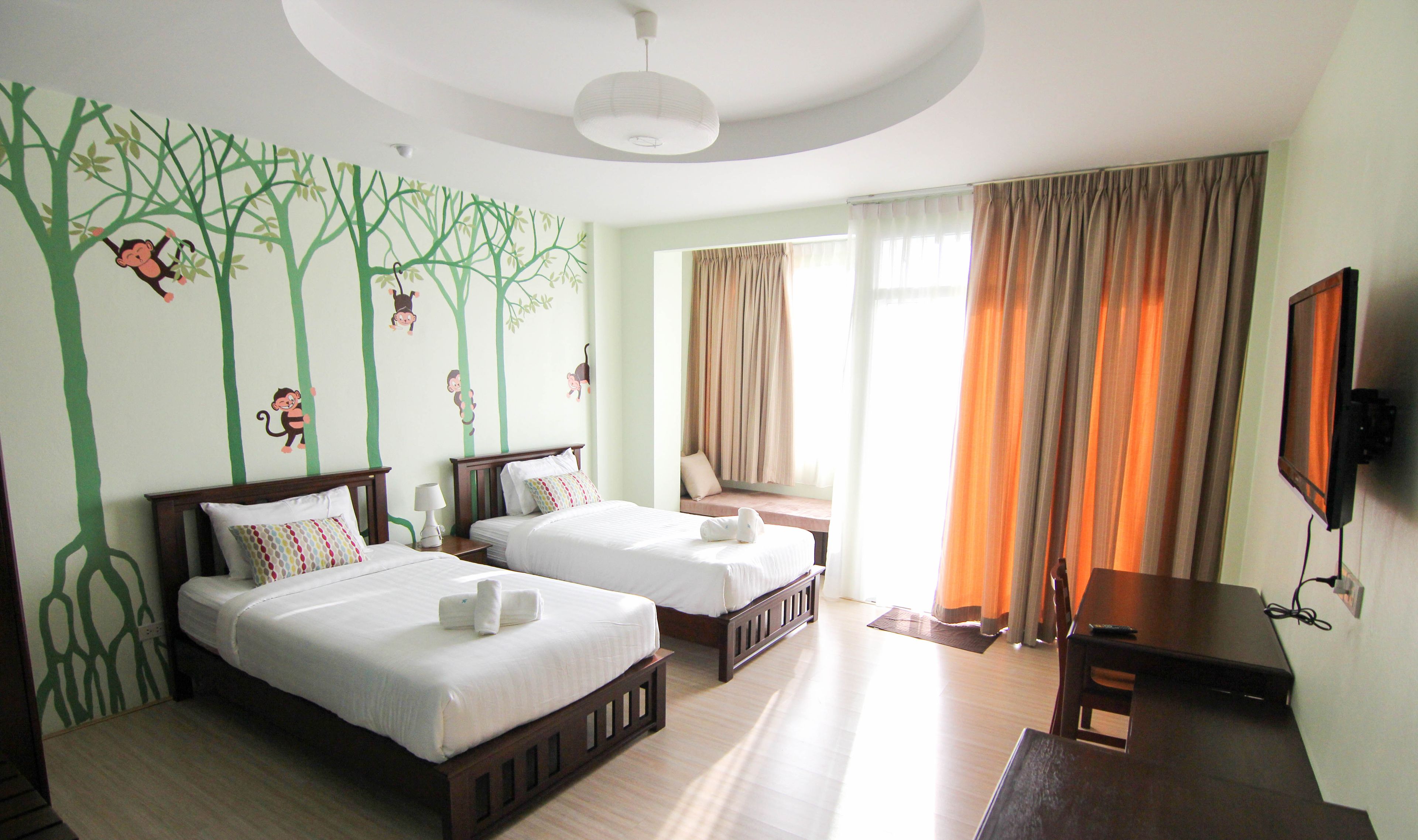 A hotel room with two beds, a TV, and a window with curtains.