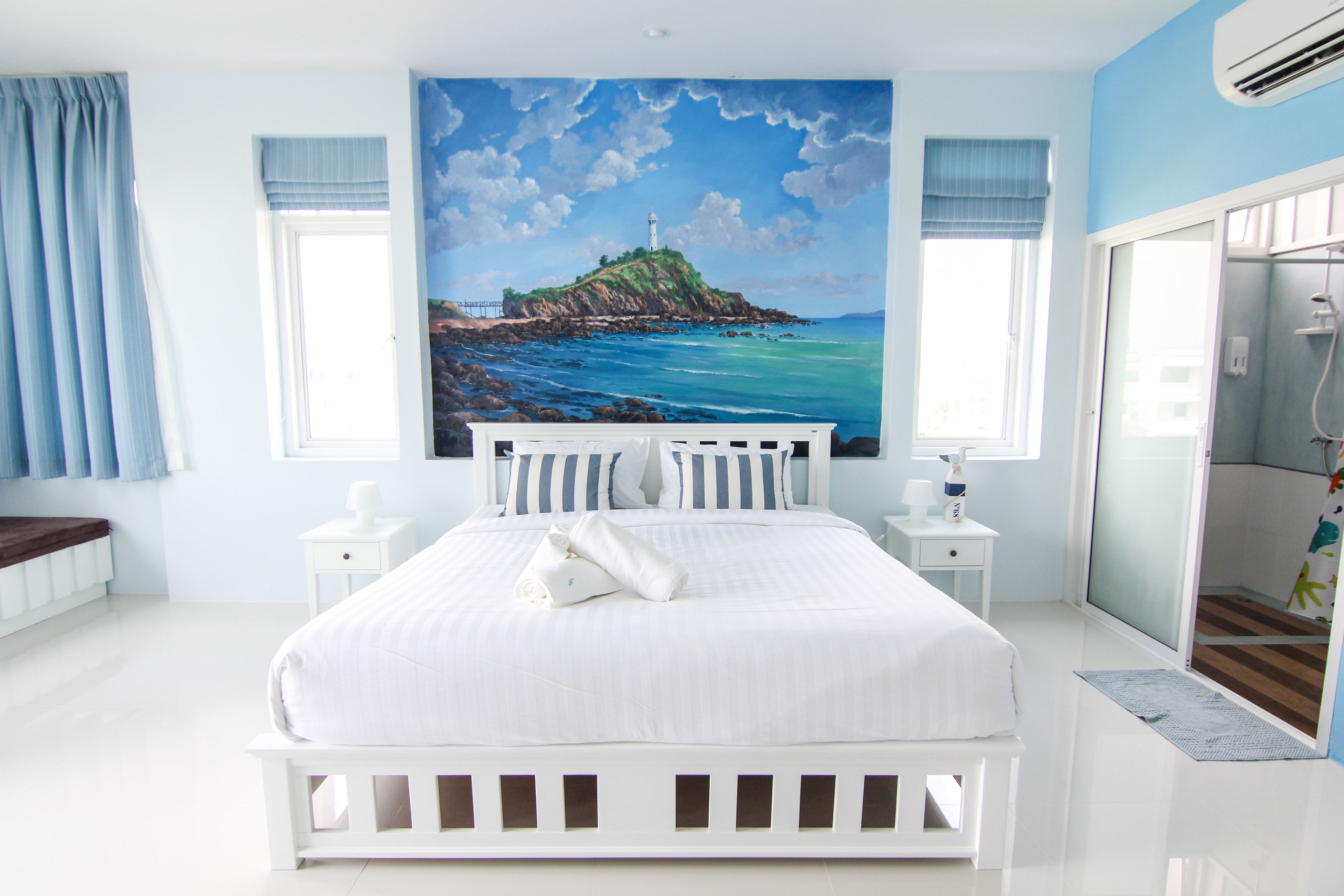 Un dormitorio con una cama grande, un cuadro de un faro y un baño con ducha.