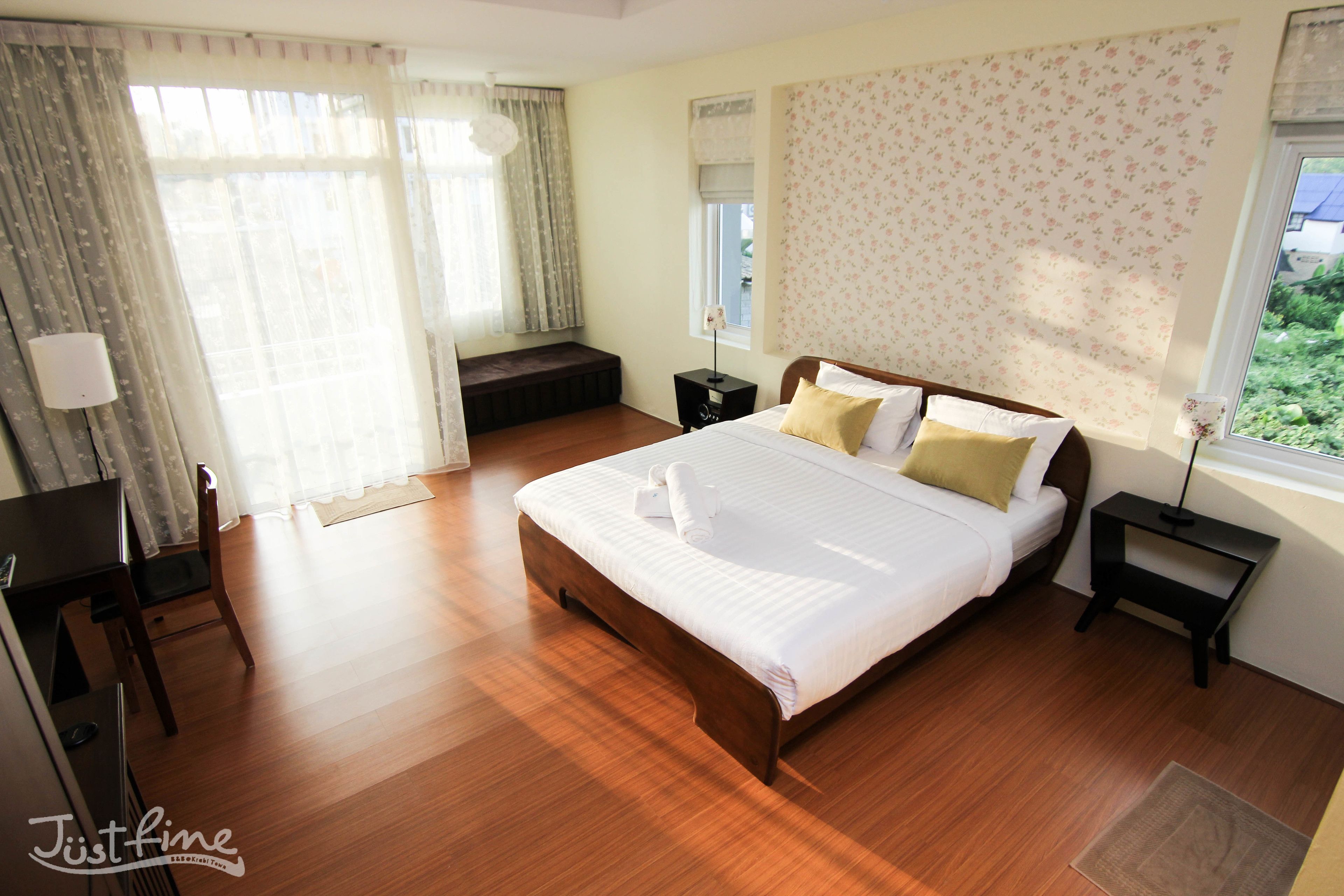 A neatly arranged bedroom with a large bed, bedside tables, a desk, and a chair.