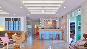 A modern hotel lobby with a reception desk, seating area, and a view of the kitchen. - Just Fine Krabi (Krabi)