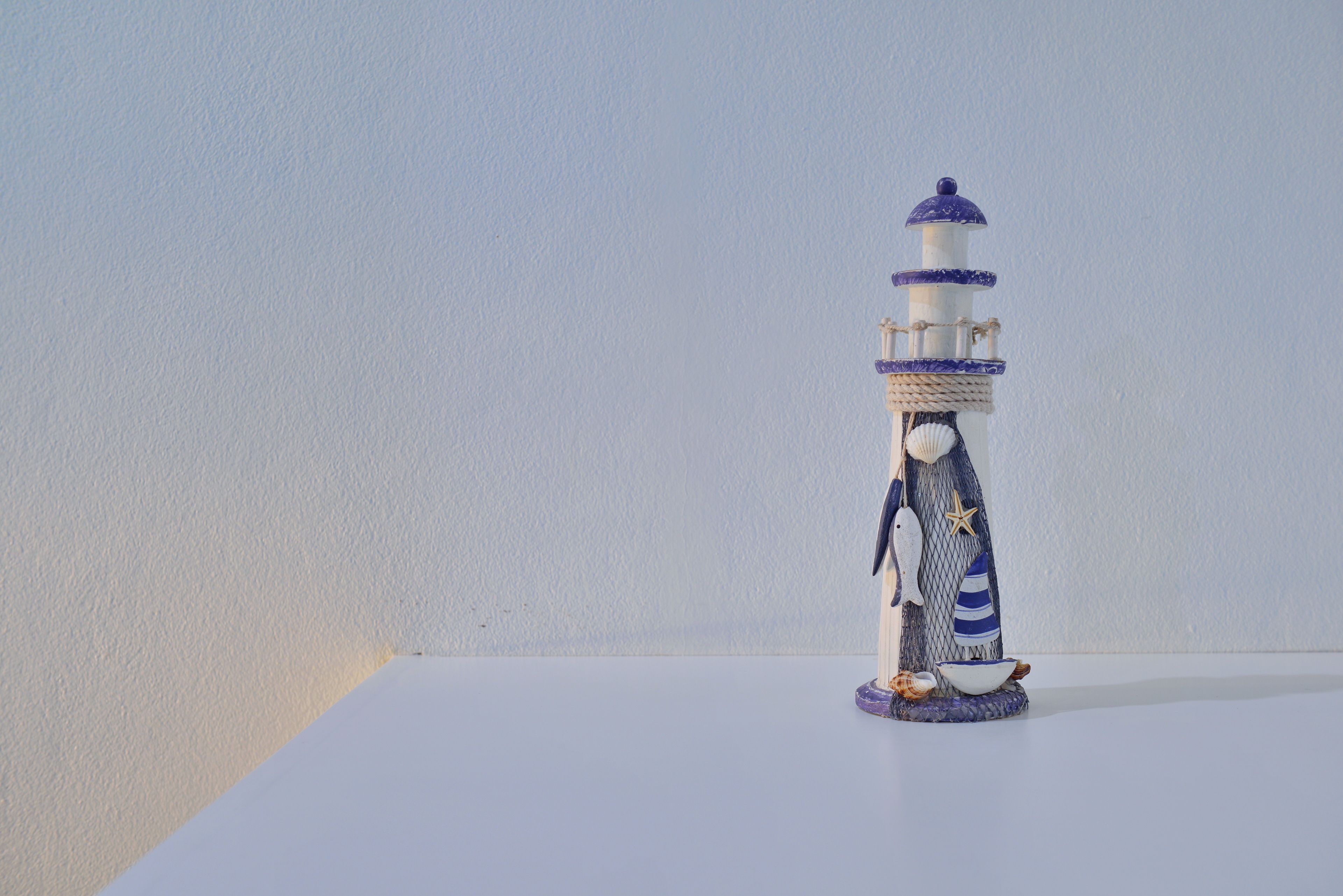 Un pequeño faro decorativo con la figura de una persona y un cuenco en su base.