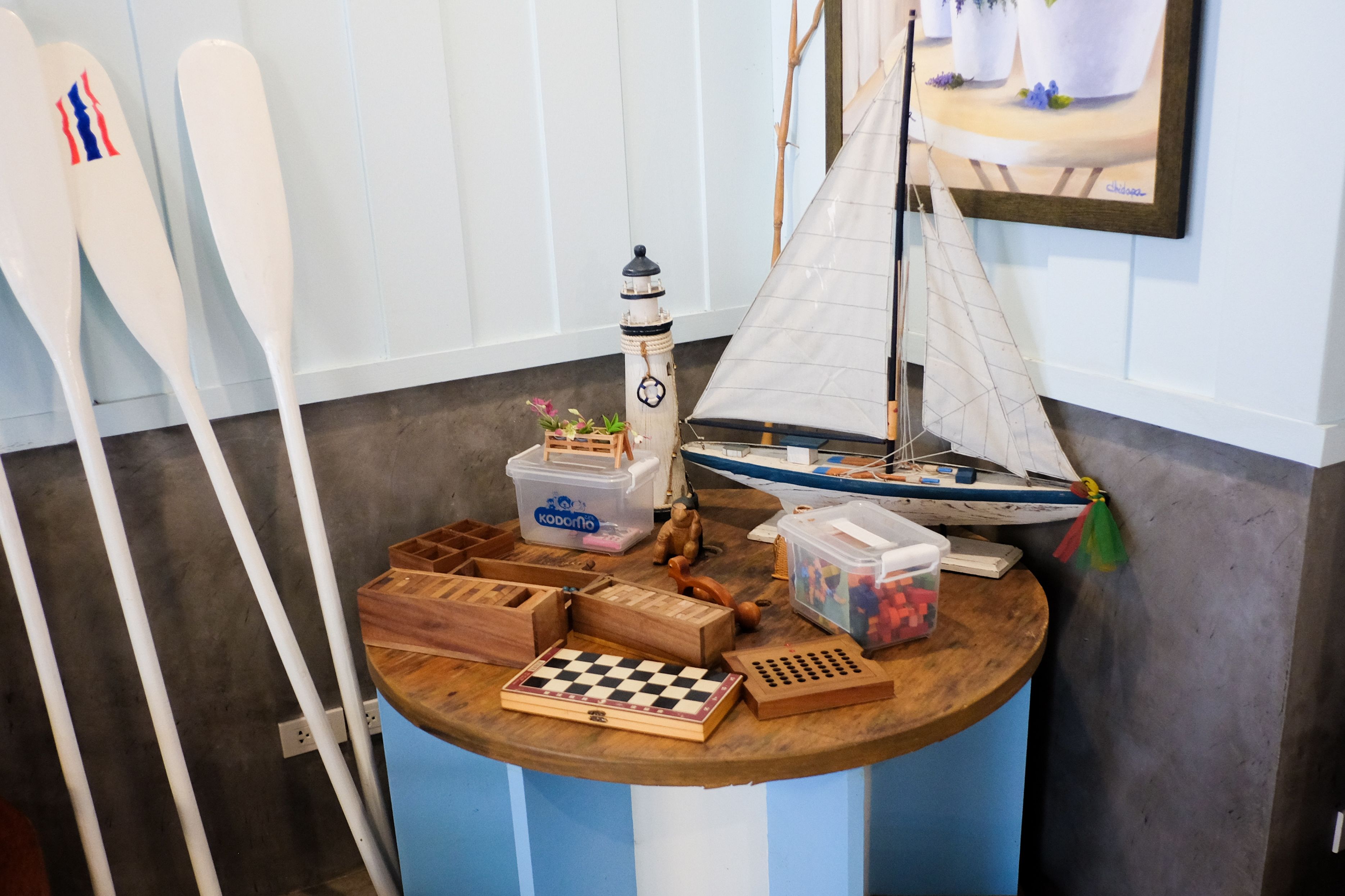 Una mesa de madera con un tablero de ajedrez, un pequeño modelo de velero y un modelo de faro.