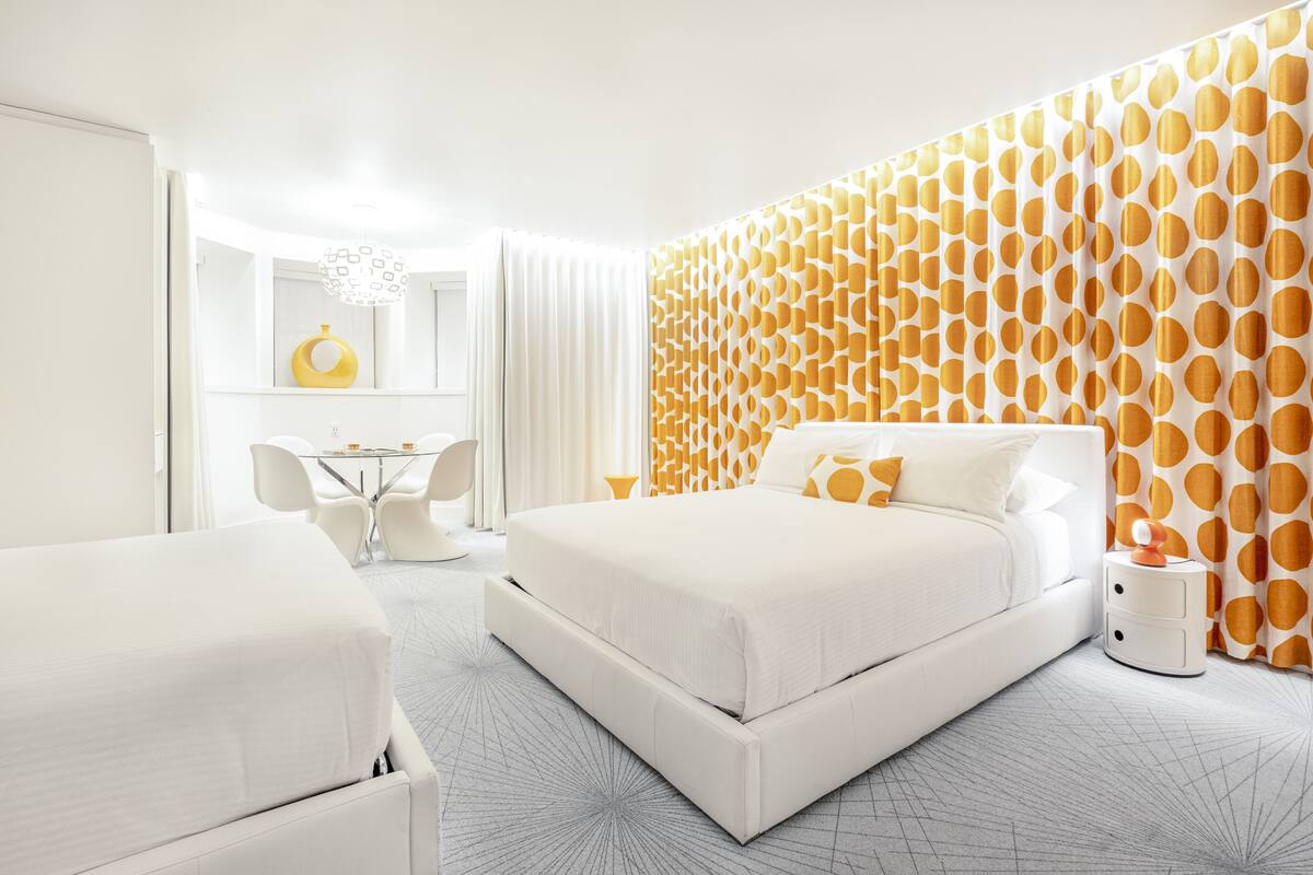 A modern hotel room with a large bed, a desk, and a chair.