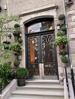 Entrada de un hotel con una reja de hierro forjado negro, plantas en macetas y un letrero que dice 'Nomad Hotel'.