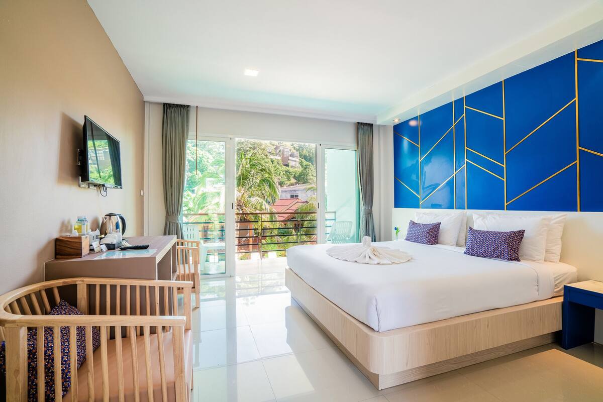 Une chambre d’hôtel moderne, dotée d’un grand lit, d’un bureau avec une chaise et d’un téléviseur fixé au mur.