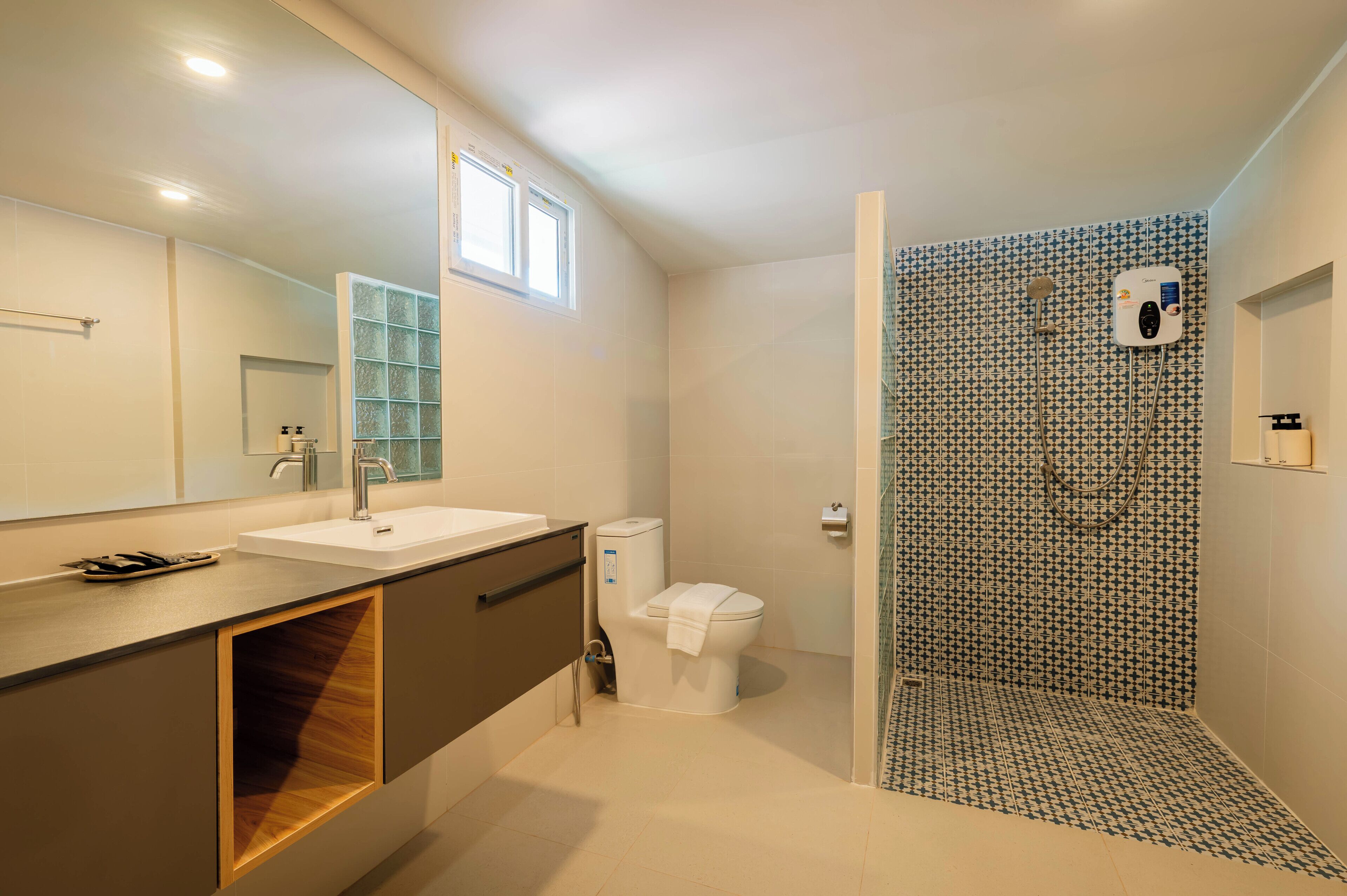 Une salle de bain moderne avec un grand miroir, un lavabo et un espace douche.