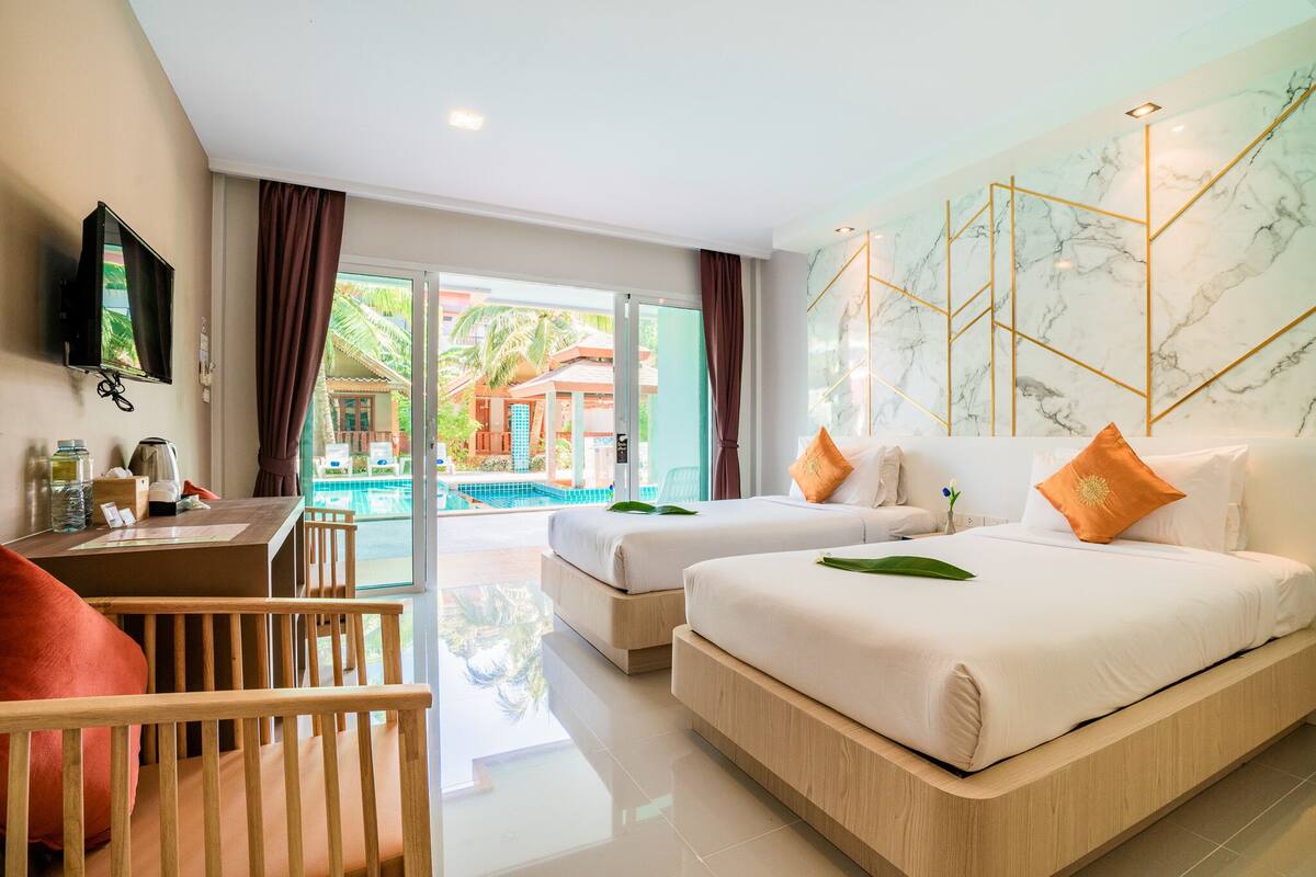 Une chambre d’hôtel avec deux lits, un bureau, une télévision et une vue sur une piscine et un espace extérieur.