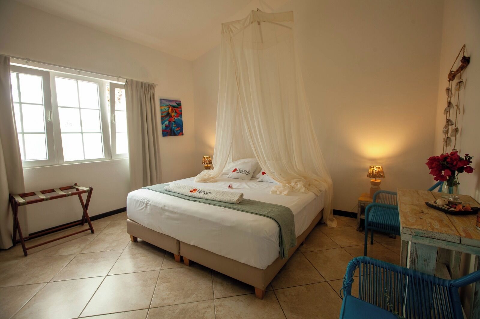 Une chambre à coucher avec un lit, une table de chevet, une chaise, une fenêtre et un tableau au mur.