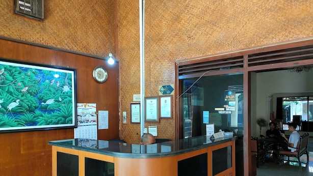 Un mostrador de recepción con detalles de madera, un mural grande en la pared y varios carteles informativos.