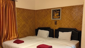 Cama doble con ropa de cama blanca y almohadas rojas, cabecera de madera y pared con diseño tejido.