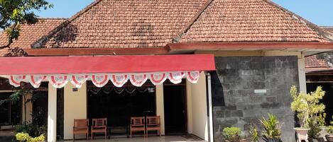 A building with a tiled roof, a covered entrance with chairs, and a sign indicating an office.