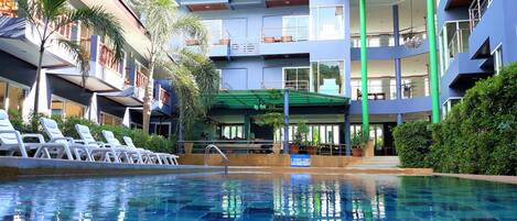 Een buitenzwembad, ligstoelen bij het zwembad