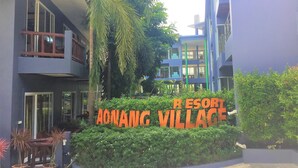 Señal de Aonang Village Resort con un edificio moderno al fondo.