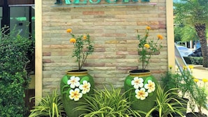 Señal para AO NANG Village Resort, con un fondo de pared de piedra y dos macetas grandes con flores.
