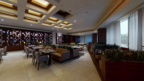 A modern dining area with multiple seating options, including tables and sofas, arranged in a spacious layout.