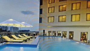 A rooftop pool with sun loungers and a building with multiple windows.