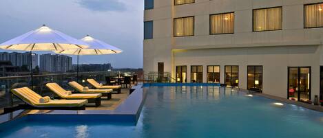 Una piscina al aire libre, sillones reclinables de piscina