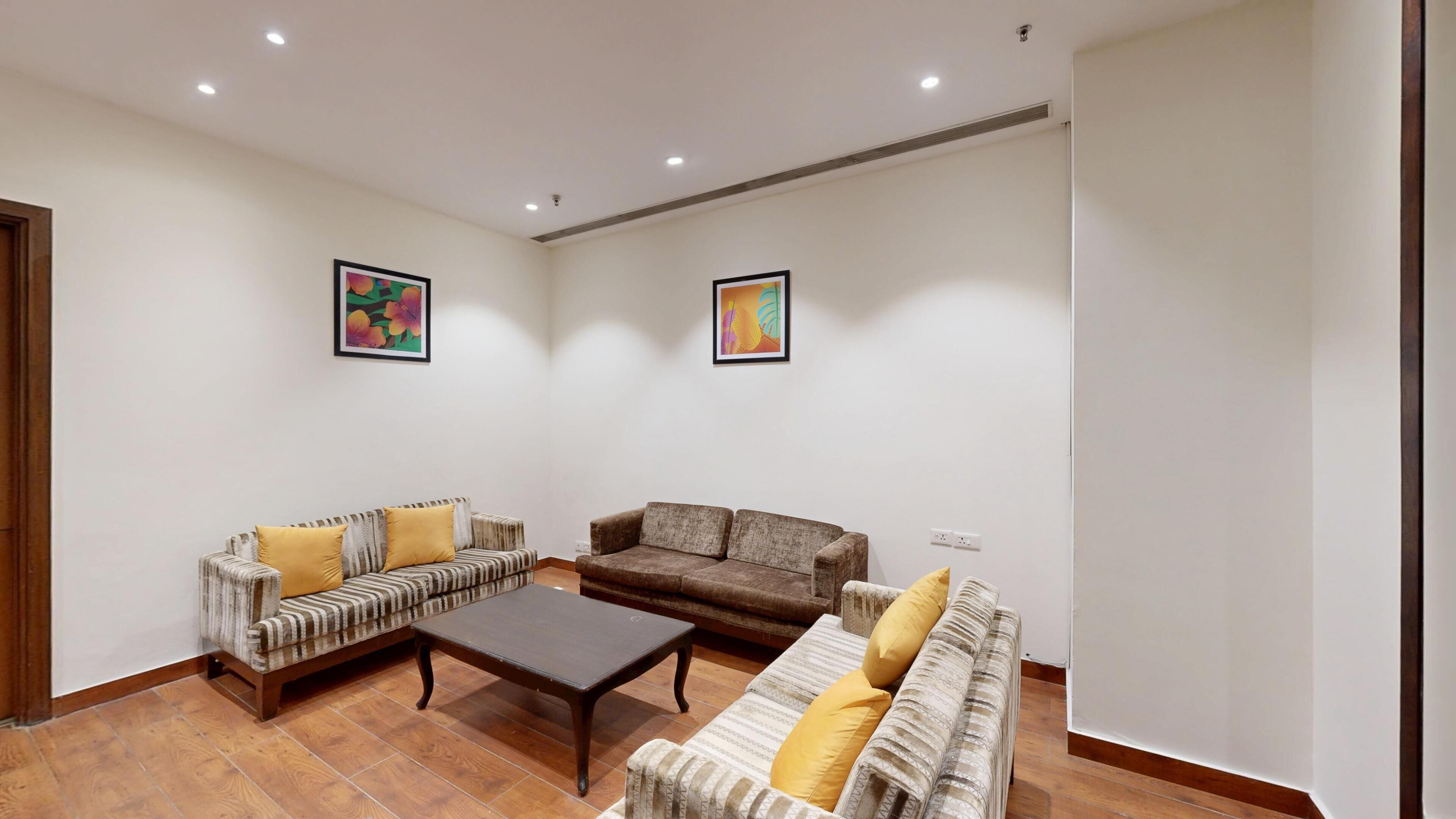 A living room with two sofas, a coffee table, and two wall-mounted paintings.