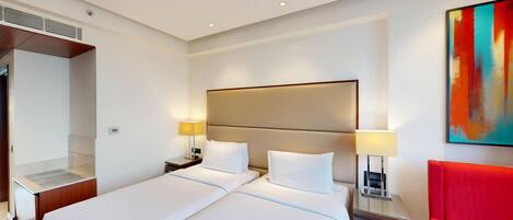 Ein Hotelzimmer mit einem großen Bett, zwei Nachttischen mit Lampen, einem roten Sessel und einem Gemälde an der Wand.
