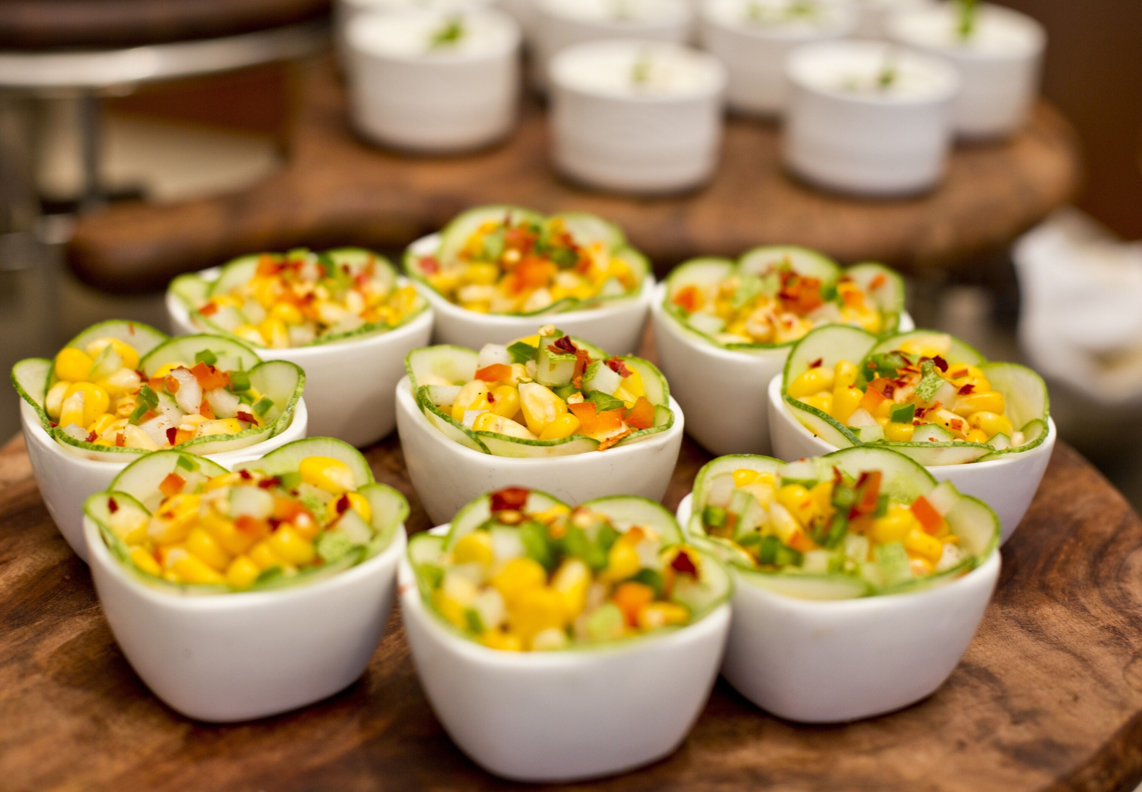 A wooden table with white bowls containing a fruit salad.