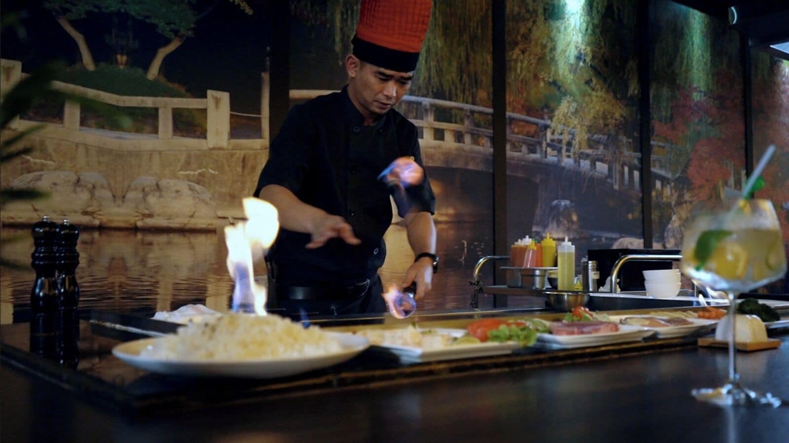 Un cocinero preparando comida en una barra con un fondo decorativo.