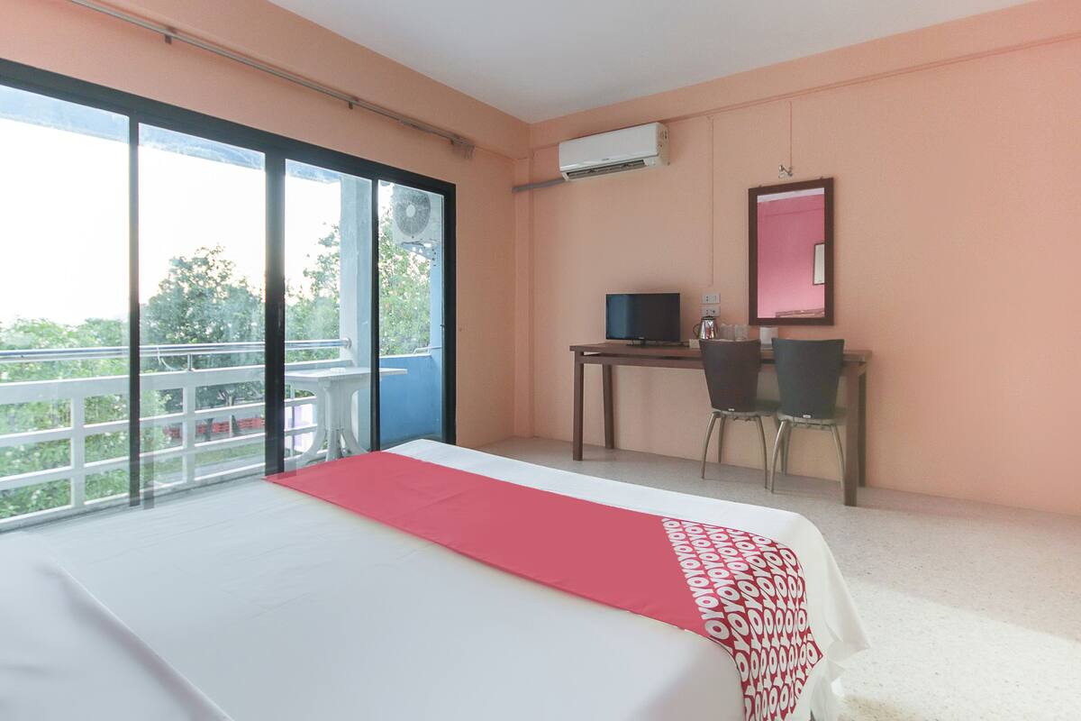 Ein Hotelzimmer mit einem großen Bett, einem Schreibtisch mit Computer, einem Stuhl und einem Balkon mit Blick.