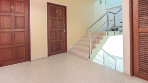 Ein Flur mit zwei Holztüren, einer Treppe mit Metallgeländern und einem beigefarbenen Boden.