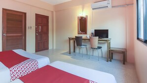 Ein Hotelzimmer mit zwei Betten, einem Schreibtisch mit Stuhl, einem Fernseher und einer Klimaanlage.