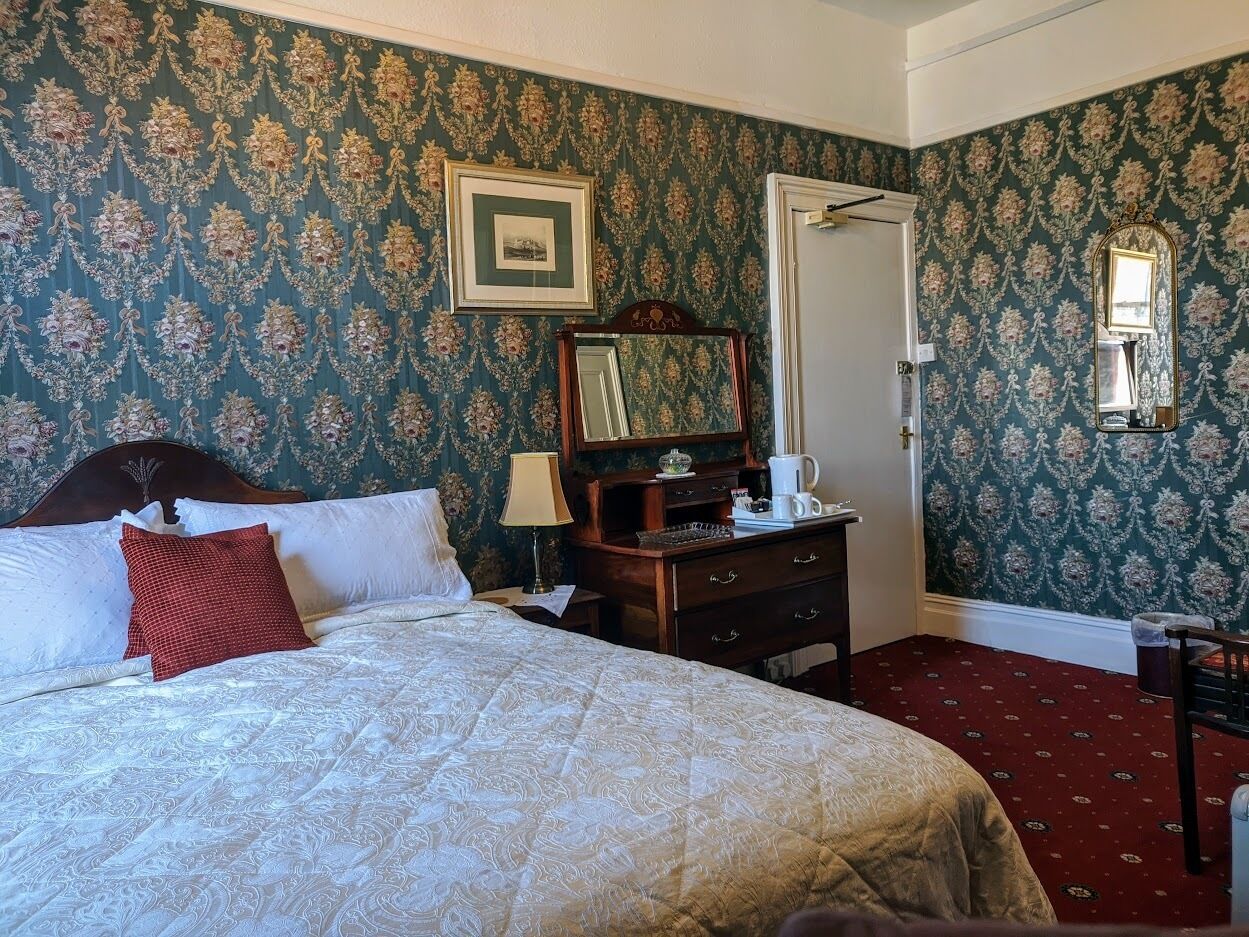 Un dormitorio con una cama grande, un aparador, un espejo y un cuadro en la pared.